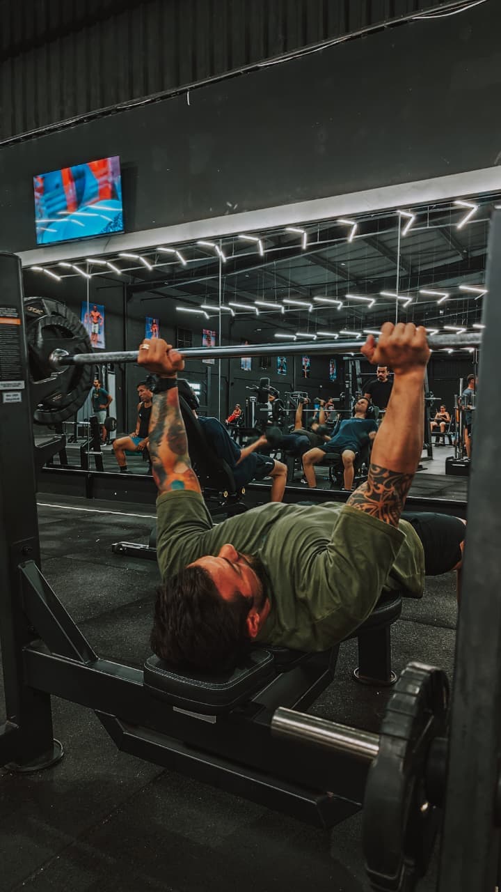 Aluno treinando supino com acompanhamento no CT Forma Fit